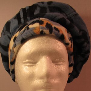 May include: A blue and brown fleece beanie with a patterned design. The beanie is folded down to show the lining.