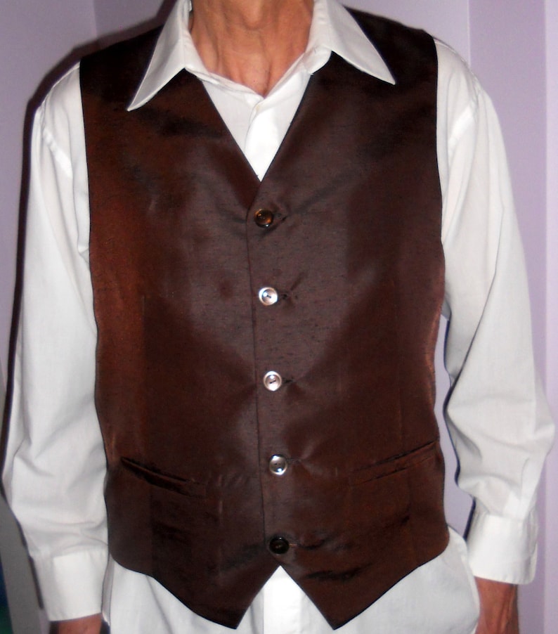 May include: A brown satin vest with five silver buttons. The vest has a pointed collar and a pocket on each side.