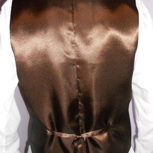 May include: A brown satin vest with a back tie closure.