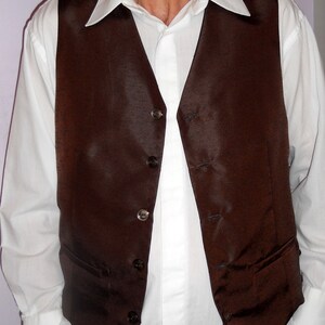 May include: A brown satin vest with a white button-up shirt underneath. The vest has a pointed collar and multiple buttons down the front.