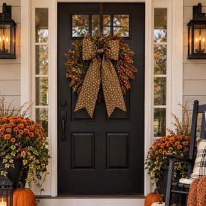 May include: A black front door with a fall wreath featuring a large brown patterned bow, a brown coir doormat with the word hello in black script, layered over a black and tan buffalo check rug, flanked by orange mums, pumpkins, and a rocking chair.