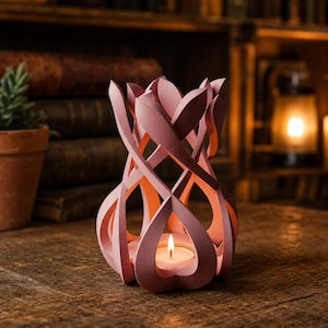 May include: A dusty pink candle holder with an intricate, open-work lattice structure that curves upward. The design features interlocking petal-like shapes that surround a central tea light candle, which emits a warm, soft glow from within.