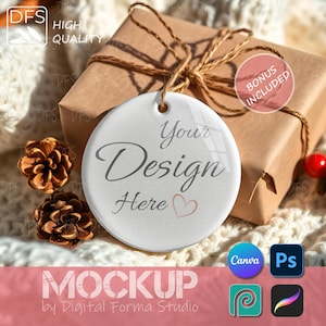 May include: A white ceramic ornament with the text "Your Design Here" and a heart graphic, hanging in front of a wrapped gift box. The image includes pinecones and the words "Bonus Included".