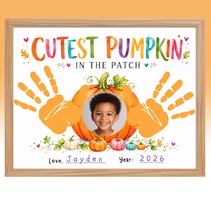 May include: A framed print featuring the text CUTEST PUMPKIN IN THE PATCH in colorful letters. The design includes two orange handprints, a central pumpkin illustration with a photo of a child, small pumpkins, and the text Love, Jayden Year: 2026.