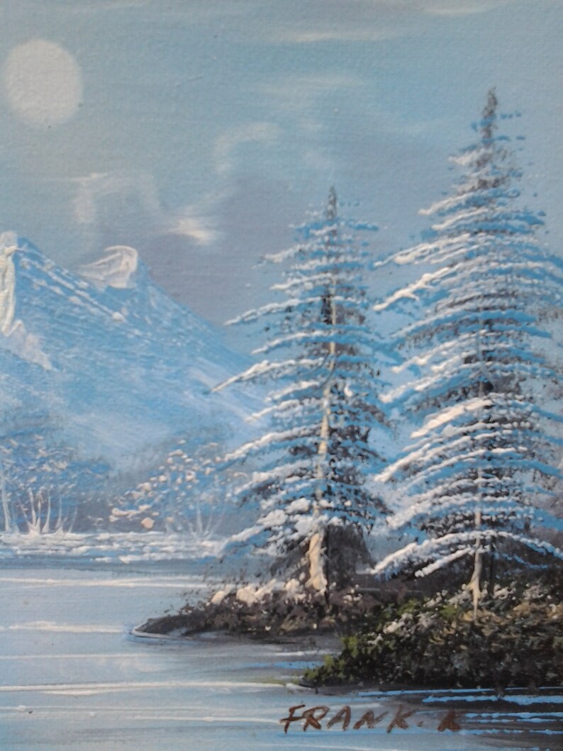 Puede incluir: Una pintura de paisaje de invierno nevado con dos altos pinos cubiertos de nieve en primer plano. Los &aacute;rboles est&aacute;n frente a un lago y monta&ntilde;as en el fondo. El cielo es de un azul claro con una luna blanca.