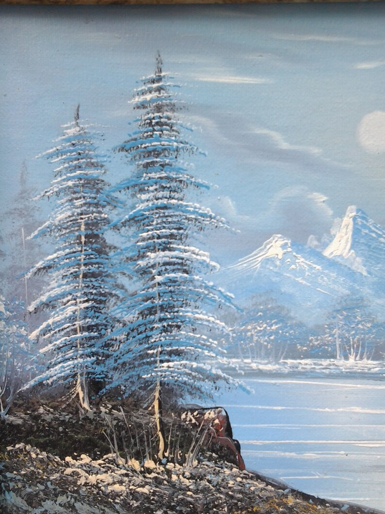 Puede incluir: Una pintura que representa una escena de invierno con dos pinos cubiertos de nieve en primer plano, un lago helado y monta&ntilde;as nevadas en el fondo.