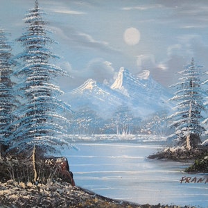 Puede incluir: Una pintura de paisaje de invierno nevado con un lago, monta&ntilde;as y pinos. El cielo es de color azul claro con luna llena. La pintura est&aacute; firmada "FRANK R."