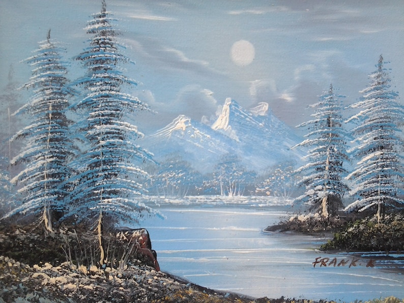 Puede incluir: Una pintura de paisaje de invierno nevado con un lago, monta&ntilde;as y pinos. El cielo es de color azul claro con luna llena. La pintura est&aacute; firmada "FRANK R."