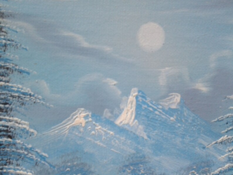 Puede incluir: Una cordillera nevada con luna llena en el cielo. Las monta&ntilde;as est&aacute;n cubiertas de nieve blanca y el cielo es de color azul claro.