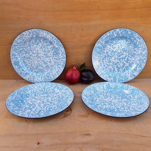 May include: Four blue and white enamel dinner plates with a black rim. The plates have a speckled pattern.