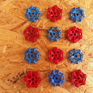 May include: A collection of twelve water valve handles in a symmetrical arrangement. The handles are in two colors, six are blue and six are red. The handles are made of a hard plastic material and are arranged on a wood grain surface.