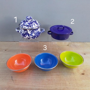 May include: Three enamelware bowls in orange, blue, and green, and two enamelware pots with lids, one with a blue and white floral pattern and the other solid blue.