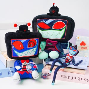 Pode incluir: Uma coleção de brinquedos de pelúcia com um design único de robô. Os brinquedos têm corpos pretos com rostos bordados em vermelho, azul e branco. Um brinquedo tem pernas e braços longos e finos. Os brinquedos são exibidos em livros.