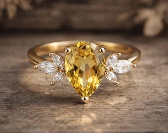 Anillo de oro con citrino en forma de pera y anillo de compromiso floral con moissanita en talla marquesa.