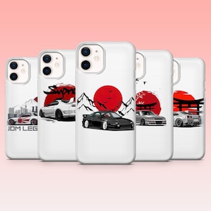 May include: White phone cases with Japanese-themed car designs. Each case features a different car illustration, a red sun, mountains, and a Japanese gate. The text "JDM LEG" is visible on one case.
