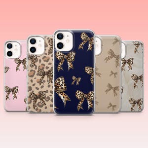 May include: A collection of five phone cases with a bow pattern. The cases feature a variety of colors, including pink, tan, navy blue, and clear. The bows have a leopard print design.