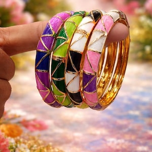 Könnte beinhalten: Ein Set aus vier goldfarbenen Metallarmreifen mit geometrischen Emaille-Einlagen. Jeder Armreif zeigt ein sich wiederholendes Dreiecksmuster in leuchtenden Farben wie Violett, Blau, Limettengrün, Schwarz, Weiß und Pink, getrennt durch feine Goldlinien.