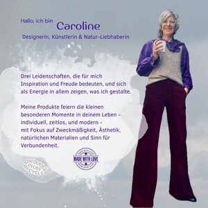 May include: A person with short gray hair wearing a purple long-sleeve shirt, a beige knit vest, and dark maroon wide-leg trousers. The image includes text in German, a 'Made With Love' circular logo, and a 'Reduce Reuse Recycle' graphic icon.