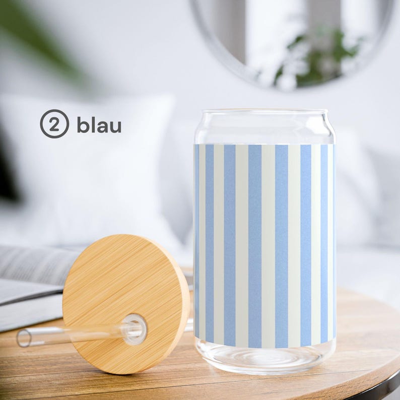 May include: A clear glass tumbler with a light blue and white vertical striped pattern. The glass features a cylindrical shape with a wide opening and includes a round bamboo lid with a central hole and a clear glass straw.