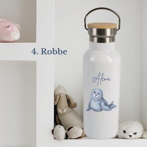 May include: A white metal water bottle with a bamboo lid and a silver handle. The bottle features a blue illustration of a seal and the name Alena printed in blue script. The text 4. Robbe is visible to the left of the bottle.