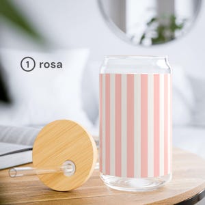 May include: A clear glass tumbler with a cylindrical shape and a flat base, featuring a vertical pink and white striped pattern. The tumbler includes a circular bamboo lid with a central hole and a straight, clear glass straw.