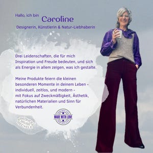 May include: A person with short gray hair wearing a purple long-sleeve shirt, a beige knit vest, and dark maroon wide-leg trousers. The image includes text in German, a 'Made With Love' circular logo, and a 'Reduce Reuse Recycle' graphic icon.