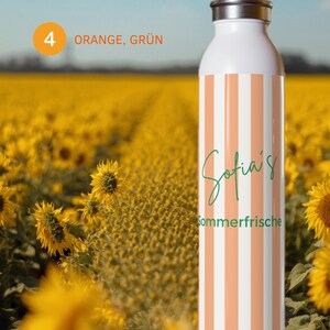May include: A white water bottle featuring vertical orange and white stripes. The text "Sofia's" is written in a green cursive script above the green printed word "Sommerfrische". The bottle has a metallic silver cap and a smooth cylindrical body.