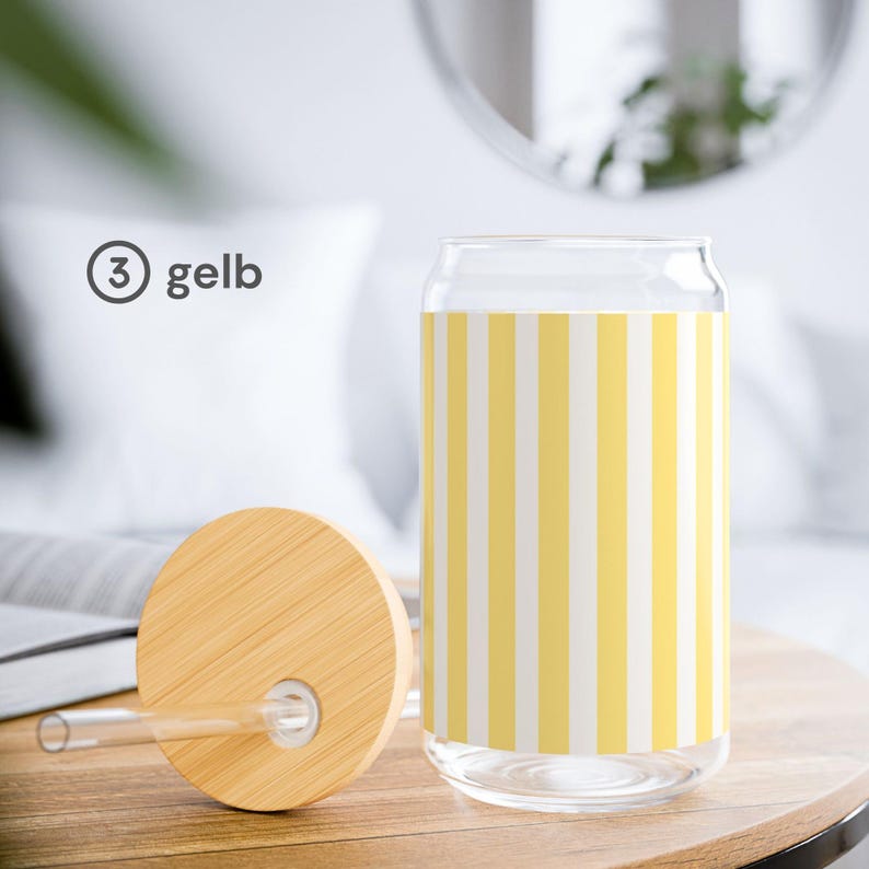 May include: A clear glass can-shaped tumbler featuring a vertical yellow and white striped pattern. The set includes a round bamboo lid with a central hole and a clear glass straw. The text 3 gelb is printed in dark gray to the left of the glass.
