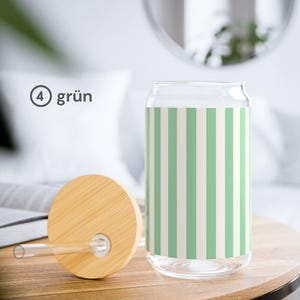 May include: A clear glass tumbler with a vertical light green and white striped pattern. The set includes a round bamboo lid with a central hole and a straight clear glass straw. The text 4 gr&uuml;n is visible on the left side of the image.