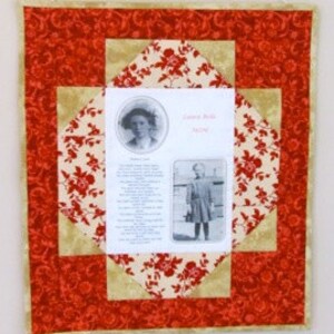 Peut inclure: Une tenture murale matelassée rouge et crème avec une photo encadrée et du texte. Le texte indique "Carol Bells 1909".