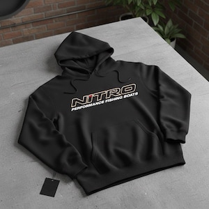 May include: Black hooded sweatshirt with the word "NITRO" in white and orange lettering, and the text "PERFORMANCE FISHING BOATS" in white. The sweatshirt has a front pocket and a drawstring hood.