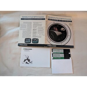 May include: A vintage computer game box set for "Rendezvous with Rama" by Arthur C. Clarke. The box features a space-themed graphic and the Trillium logo. Includes floppy disks and a white envelope.