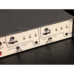 May include: A dark gray electronic control panel with a cream-colored faceplate featuring multiple metal toggle switches, sliding switches labeled FULL, OFF, ON, H, S, V, and circular indicator lights. The panel includes labels for AUTO, MAN, and RESET.