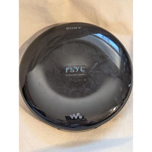 May include: A black Sony PSYC CD Walkman D-NE800. The portable CD player features the Sony logo at the top and the PSYC logo in the centre. The Walkman logo is at the bottom. The CD player is round with a glossy finish.