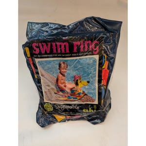 May include: A vintage inflatable swim ring packaged in a dark blue plastic bag. The packaging features the text SWIM RING and an illustration of a child sitting on a colorful duck-shaped float in a pool. The label indicates a size of 21x18 inches.
