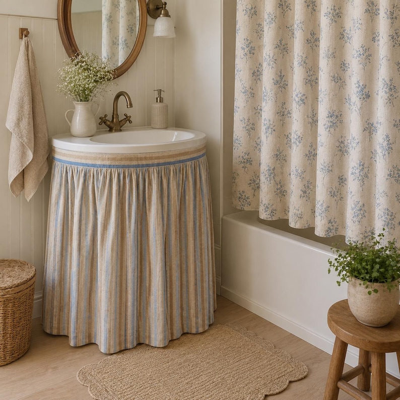Sky blue stripe viscose linen blend sink skirt installed around a bathroom pedestal sink, adding stylish concealed storage with a fresh cottage-inspired look.