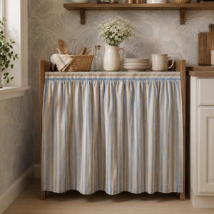 Sky blue stripe viscose linen blend cabinet curtain installed on a farmhouse kitchen cabinet using hook and loop tape for easy no-drill installation.