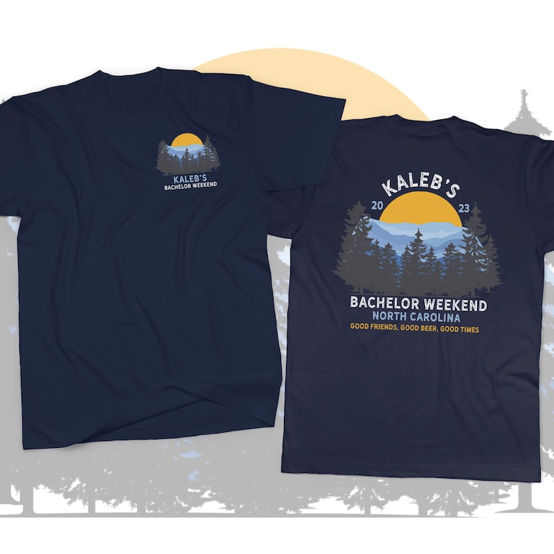 May include: A navy blue t-shirt with a graphic of a mountain range and a yellow sun. The text "Kaleb's Bachelor Weekend 2023" is printed on the shirt. The text "Bachelor Weekend North Carolina" and "Good friends, good beer, good times" is also printed on the shirt.