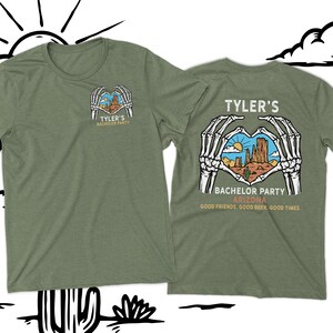 May include: Green t-shirt with a skeleton hand heart design. The heart contains a desert landscape with the text "Tyler's Bachelor Party Arizona. Good friends, good beer, good times."