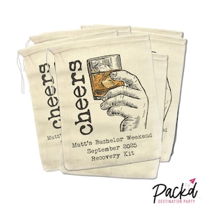 May include: Set of four beige canvas bags with a hand drawn illustration of a hand holding a glass of whiskey. The bags have the text "cheers" printed on them and the text "Matt's Bachelor Weekend September 2025 Recovery Kit".