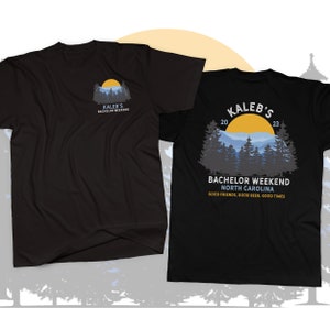 May include: Black t-shirt with a mountain scene and the text "Kaleb's Bachelor Weekend 2023 North Carolina Good Friends, Good Beer, Good Times" printed on the back. The front of the shirt has the text "Kaleb's Bachelor Weekend" printed on the left chest.
