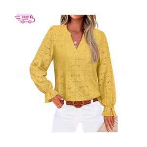Puede incluir: Una blusa amarilla de manga larga con cuello en V y un patrón de encaje floral. La blusa tiene un puño con volantes y se combina con pantalones blancos y un cinturón marrón. También se incluye un icono de envío gratuito.