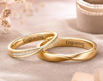 May include: Two gold rings with a twisted band design. One ring features a row of small clear stones set along the twist, while the other is a plain polished gold band. Both rings have the word Engraving printed on the inner surface.