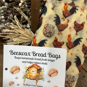 May include: Beeswax bread bags with a rooster print. The bags are designed to keep homemade bread fresh longer and reduce mold. The image also shows a card with the text "Beeswax Bread Bags" and illustrations of bread, a beehive, and bees.