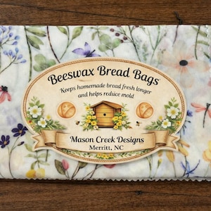 May include: Beeswax bread bags with a floral pattern in shades of purple, pink, and yellow. The bags feature a label that reads "Beeswax Bread Bags" and "Mason Creek Designs, Merritt, NC."