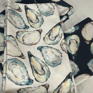 May include: Set of four white cotton napkins with a blue and white oyster print. The napkins are folded and stacked on top of each other.