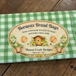 May include: A green and white checkered beeswax bread bag. The bag has an oval label with the text "Beeswax Bread Bags" and "Keeps homemade bread fresh longer and helps reduce mold". The label also includes the text "Mason Creek Designs, Merritt, NC".