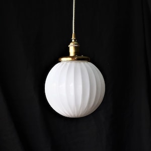 May include: A white ribbed glass globe pendant light fixture with a brass finish.