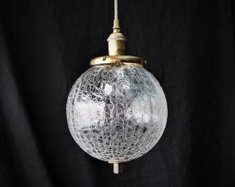 May include: A gold pendant light with a clear, cracked glass globe shade.