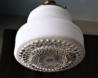 May include: White glass pendant light fixture with a brass ceiling mount and a clear glass diffuser with a textured pattern.